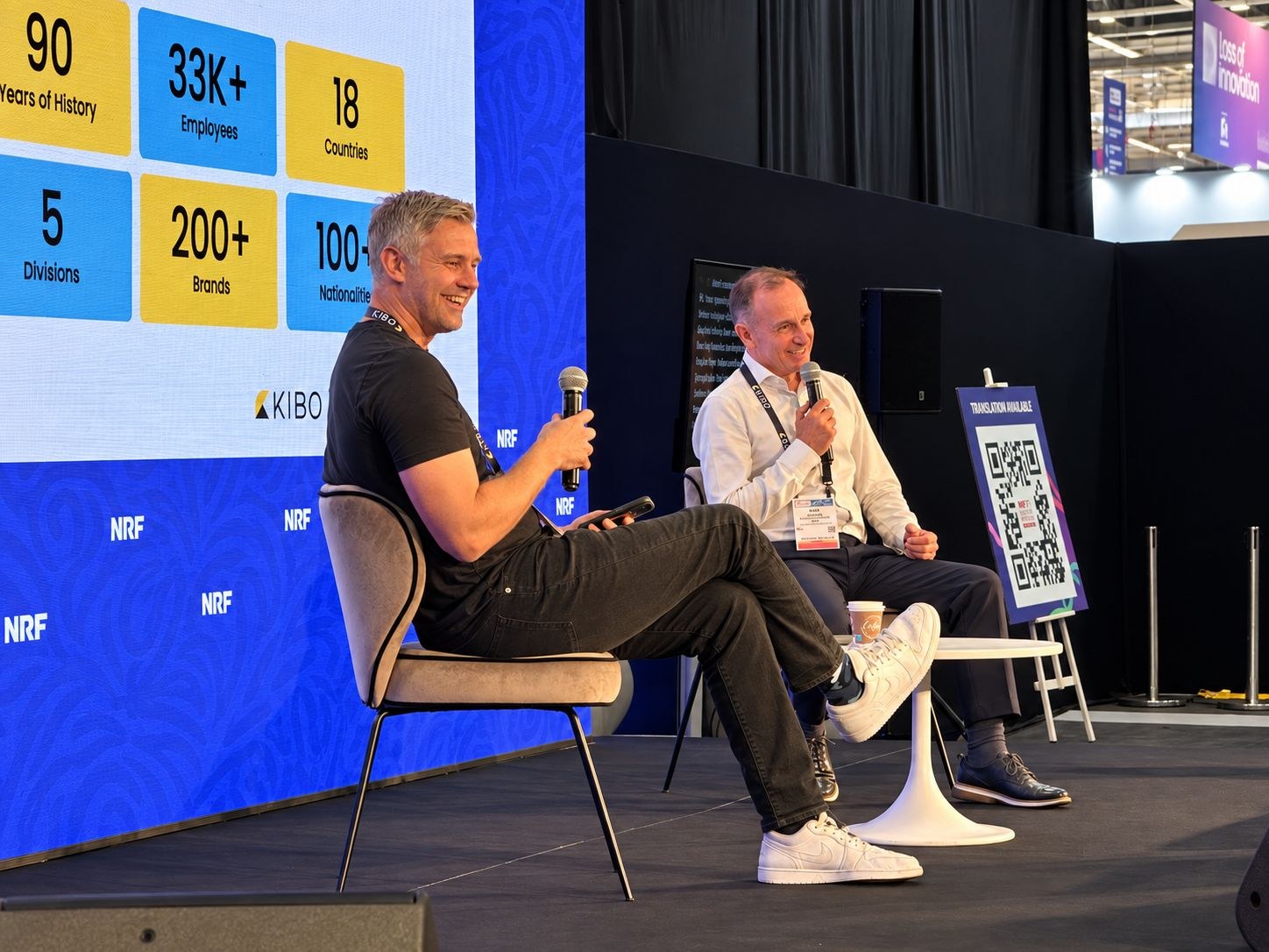 Al-Futtaim and KIBO Commerce speakers on stage at NRF Retail's Big Show Europe in Paris, with a KIBO stat screen showing 90 years of history, 33K+ employees and 18 countries