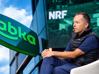 Żabka store sign beside Tomasz Blicharski speaking on stage at NRF Europe in Paris