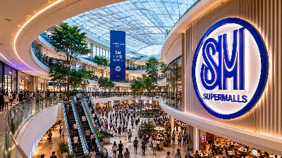 SM Supermalls storefront in the Philippines with crowds of shoppers gathering in a landscaped open plaza at sunset